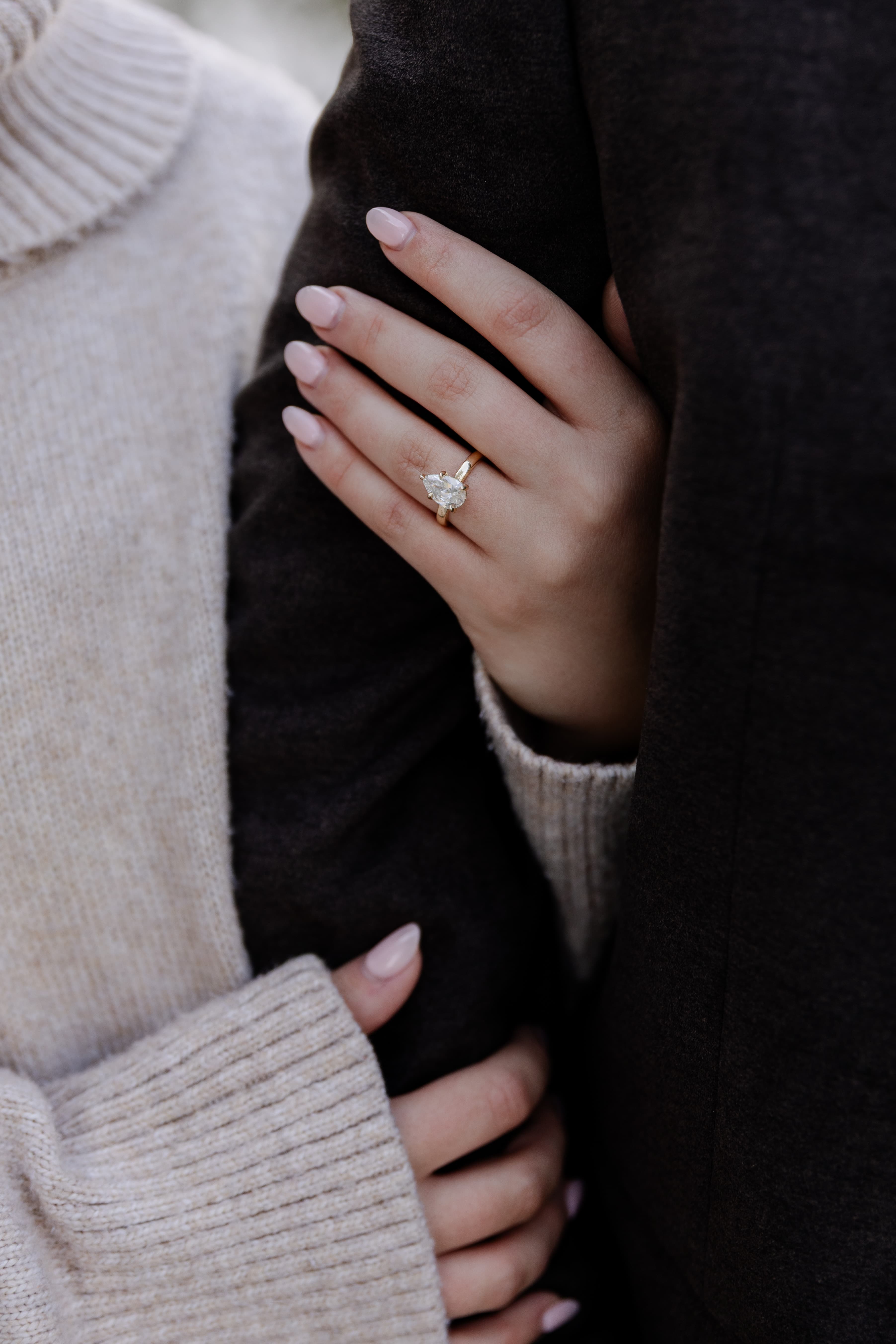 Caroline's hand resting on Joamni's arm, showing the engagement ring